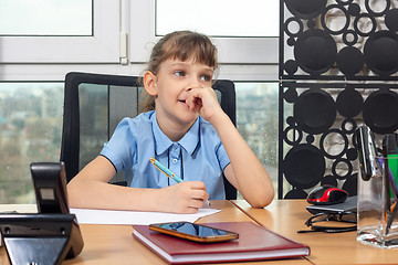 Image showing Eight-year-old girl thoughtful at the table in the office