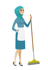 Image showing Young muslim housemaid sweeping floor with a broom
