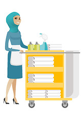 Image showing Muslim chambermaid pushing cart with bed clothes.