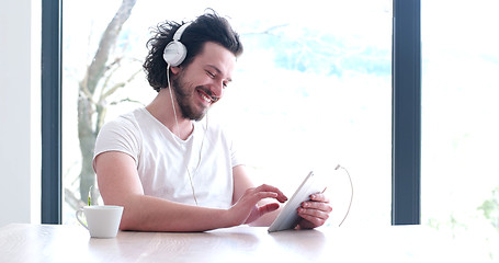 Image showing young man listenig music on tablet at home