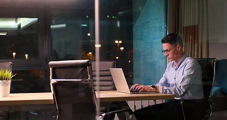 Image showing man working on laptop in dark office