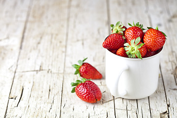 Image showing Organic red strawberries in white ceramic cup on rustic wooden b