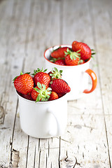 Image showing Organic red strawberries in two white ceramic cups on rustic woo