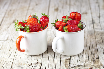 Image showing Organic red strawberries in white ceramic cups on rustic wooden 