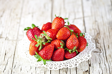 Image showing Organic red strawberries on white plate on rustic wooden backgro
