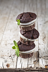 Image showing Three fresh dark chocolate muffins with mint leaves.