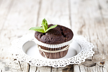 Image showing Fresh dark chocolate muffin with mint leaves on white plate