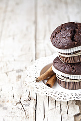 Image showing Fresh dark chocolate muffins with cinnamon sticks on white plate