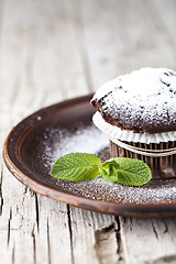 Image showing Fresh chocolate dark muffin with sugar powder and mint leaf on b