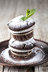 Image showing Fresh chocolate dark muffins with sugar powder and mint leaf on 