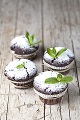 Image showing Fresh chocolate dark muffins with sugar powder and mint leaf on 