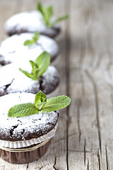 Image showing Fresh chocolate dark muffins with sugar powder and mint leaf on 