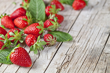 Image showing Fresh red strawberries and mint leaves on rustic wooden backgrou