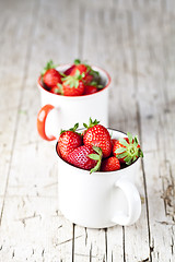 Image showing Organic red strawberries in two white ceramic cups on rustic woo