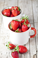 Image showing Organic red strawberries in two white ceramic cups on rustic woo