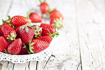 Image showing Organic red strawberries on white plate on rustic wooden backgro