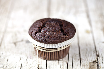 Image showing Fresh single chocolate dark muffin on rustic wooden table.