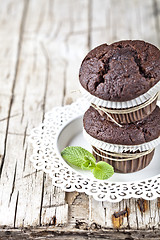 Image showing Two fresh dark chocolate muffins with mint leaves on white plate