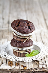 Image showing Two fresh dark chocolate muffins with mint leaves on white plate
