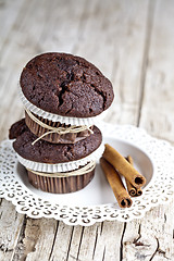 Image showing Fresh dark chocolate muffins with cinnamon sticks on white plate