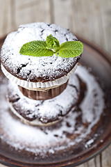 Image showing Fresh chocolate dark muffins with sugar powder and mint leaf on 