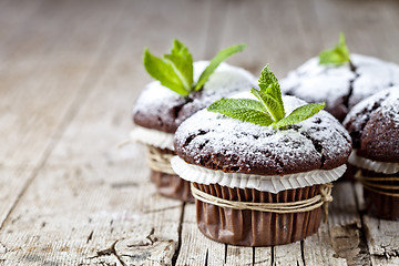 Image showing Fresh chocolate dark muffins with sugar powder and mint leaf on 