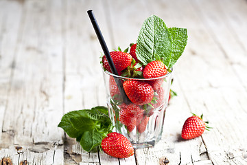 Image showing Organic red strawberries glass and mint leaves on rustic wooden 