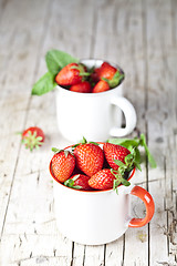 Image showing Organic red strawberries in two white ceramic cups and mint leav