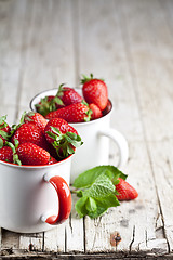 Image showing Organic red strawberries in two white ceramic cups and mint leav