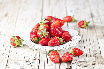 Image showing Organic red strawberries on white plate on rustic wooden backgro