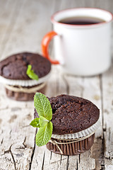 Image showing Fresh dark chocolate muffins with mint leaves and cup of tea on 