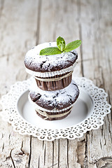 Image showing Chocolate dark muffins with sugar powder and mint leaf on white 