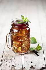 Image showing Traditional iced tea with lemon, mint leaves and ice cubes in gl