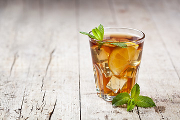 Image showing Traditional iced tea with lemon, mint leaves and ice in glass on