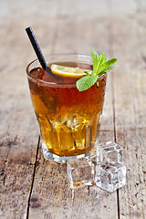 Image showing Traditional iced tea with lemon, mint leaves and ice cubes in gl