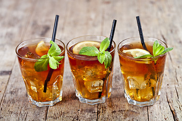 Image showing Traditional iced tea with lemon, mint leaves and ice cubes in gl