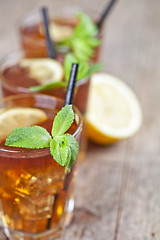 Image showing Traditional iced tea with lemon, mint leaves and ice cubes in gl