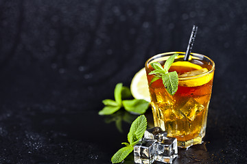 Image showing Traditional iced tea with lemon, mint leaves and ice cubes in gl