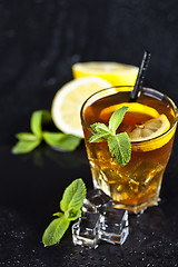 Image showing Traditional iced tea with lemon, mint leaves and ice cubes in gl