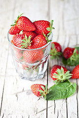 Image showing Organic red strawberries glass and mint leaves on rustic wooden 