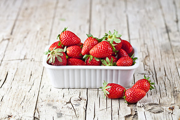 Image showing Fresh red strawberries in white bowl and mint leaves on rustic w