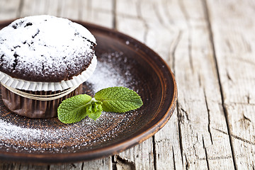 Image showing Fresh chocolate dark muffin with sugar powder and mint leaf on b