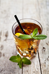 Image showing Traditional iced tea with lemon, mint leaves and ice cubes in gl