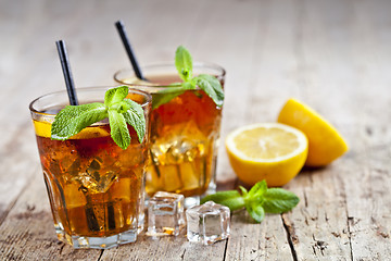 Image showing Traditional iced tea with lemon, mint leaves and ice cubes in gl