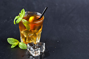 Image showing Traditional iced tea with lemon, mint leaves and ice cubes in gl