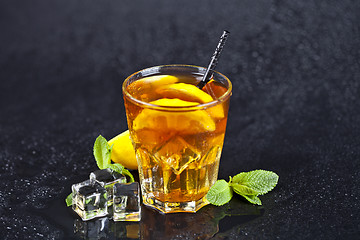 Image showing Traditional iced tea with lemon, mint leaves and ice cubes in gl