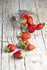 Image showing Organic red strawberries in glass on rustic wooden background.