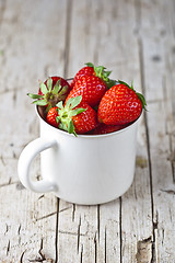 Image showing Organic red strawberries in white ceramic cup on rustic wooden b