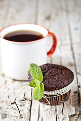 Image showing Fresh dark chocolate muffin with mint leaves and cup of coffee o