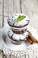Image showing Chocolate dark muffins with sugar powder, cinnamon sticks and mi